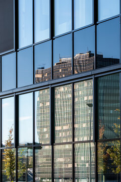 Reflection in glass windows draws a grid across the tower facade giving modern urban architecture pattern rhythm from street level