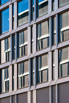 Repetitive windows trace a modern grid across an office facade creating minimal architecture pattern symmetry and disciplined urban rhythm