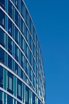 Curved glass building facade reaches into open sky with copy space minimal urban exterior architecture modern lines for technology presentation