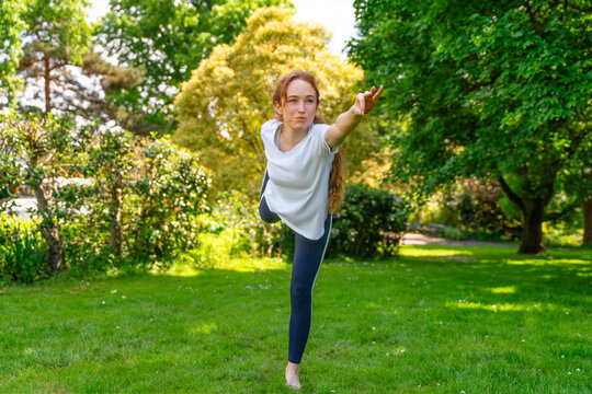 Woman practices yoga pose outside in green park during sunny day