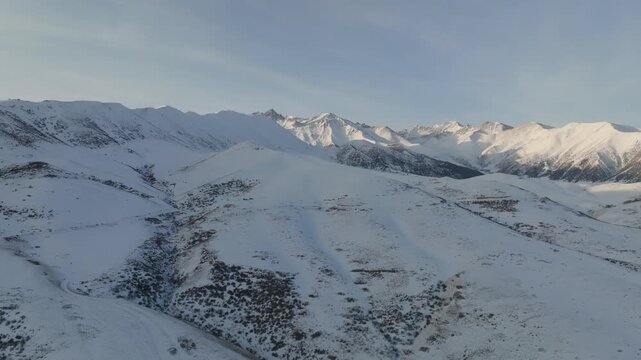 Drone footage of wide winter landscape in Chunkurchak Valley, Chuy Region, Kyrgyzstan, with snow covered ridges and peaks under soft morning light