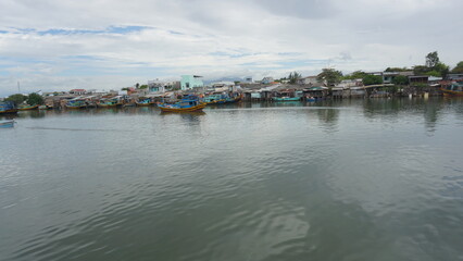 Obraz premium Riverside fishing village scenery in Binh Thuan Vietnam traditional coastal settlement boats river life local culture landscape