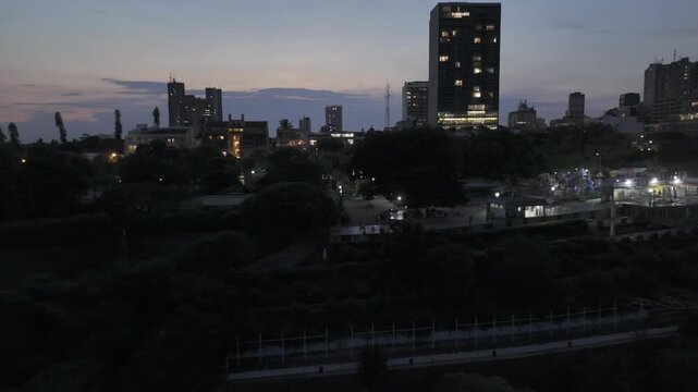 Drone flies backwards from Parque dos Namorados at sunset in Maputo, Mozambique