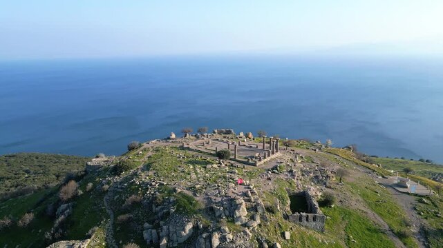 Aerial view of the ancient Temple of Athena ruins on the acropolis of Assos (Behramkale) over the Aegean Sea in Canakkale, Turkey. 4K resolution stock footage. High quality 4k footage
