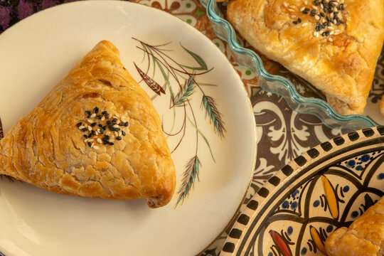 Samosa made from puff pastry. A triangular pie with meat filling, sprinkled with sesame seeds.