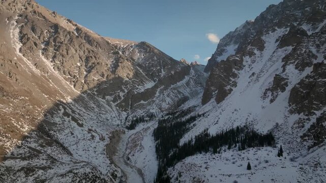 Scenic sunrise over rugged snow-covered mountain ridge in Ala-Archa National Park, Kyrgyzstan, with soft golden light, winter peaks, and clear sky
