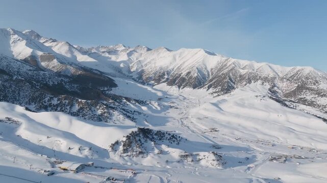 Aerial footage of the snow-covered Chunkurchak Valley with ski lifts, slopes, and mountain ridges under clear blue sky, near Bishkek, Chuy Region, Kyrgyzstan