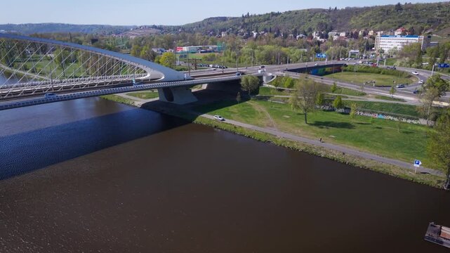 Aerial view of modern Troja Bridge with public transport tram and bus crossing Vltava river toward Hole&scaron;ovice district in Prague on a sunny day