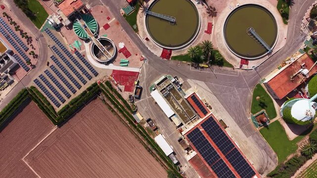 Modern wastewater treatment plant with circular clarifiers, biological nitrogen and phosphorus removal tanks, solar panels and anaerobic digesters viewed from above