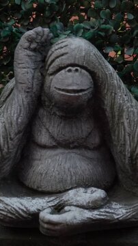 Close-up of an orangutan statue covering its eyes, symbolizing the see no evil concept. Expressive animal figurine ideal for themes of ignorance, denial, humor and philosophical symbolism.