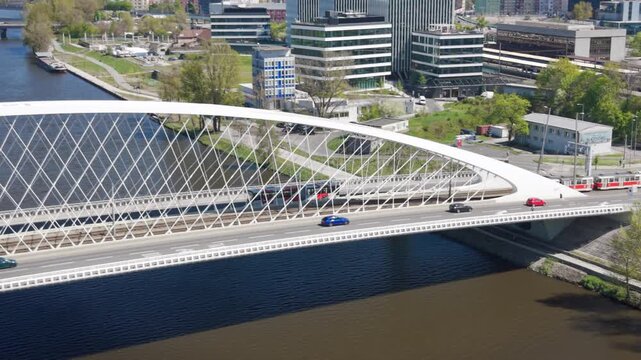 Aerial view of modern Troja Bridge with public transport tram and bus crossing Vltava river toward Hole&scaron;ovice district in Prague on a sunny day