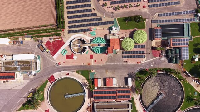 Overhead view of modern water treatment plant featuring biological treatment tanks, ozonation systems, solar panels, and circular clarifier basins surrounded by agricultural fields