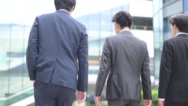 都会のビル背景で横並びで歩く3人でハンサムな営業チーム、法人営業や企業成長など若手から管理職のポジティブイメージ顔無し全身の動画　未来や希望スローモーション
