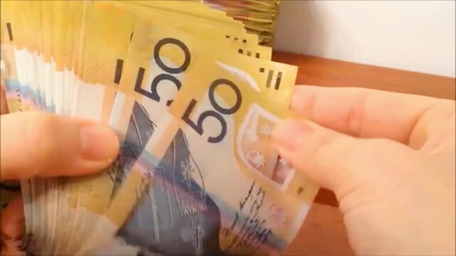 A successful entrepreneur counting cash profit in Australian fifty-dollar bills for financial investment.