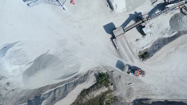 Aerial view of Foamed Glass UK Industrial Factory showing a front loader moving white material near conveyor belts and large stockpiles in Great Heck, England, United Kingdom.