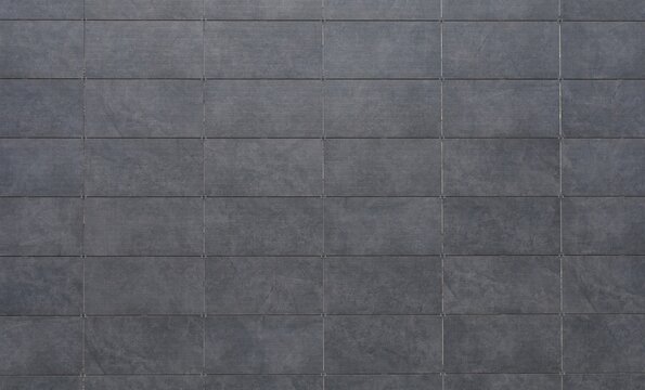 Dark gray sintered stone tiles coating of a ventilated facade. Background and texture.