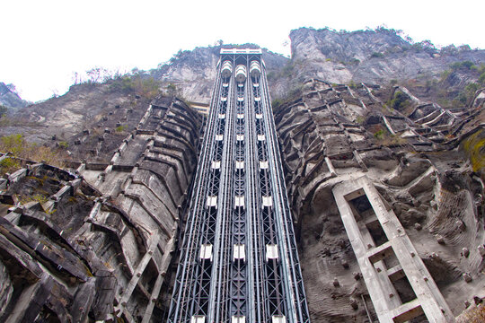 Panoramic glass capsule elevator mounted on steep mountain cliff, showcasing advanced engineering breathtaking vertical transportation. Modern scenic lift offers dramatic of rugged rock formations.