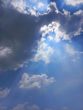 Dramatic Vertical View of Sun Hiding Behind Clouds with Silver Lining Effect