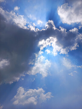 Dramatic Vertical View of Sun Hiding Behind Clouds with Silver Lining Effect