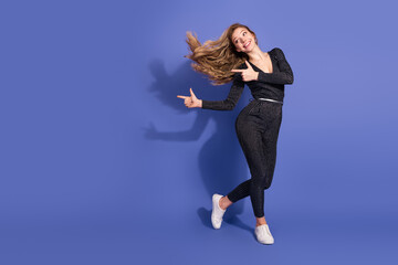 Young woman in striped jumpsuit dances against a violet background smiling and posing for a fashion image advertising fashion lifestyle and shopping campaigns © deagreez