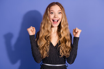 Young woman with long blonde hair in a striped jumpsuit celebrates with a joyful smile against a...