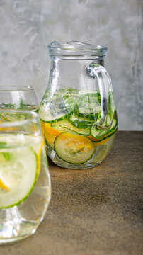 Glass pitcher filled with refreshing cucumber, lemon, and mint beverage, placed on rustic wooden table, showcasing vibrant colors and textures, phone background with copy space