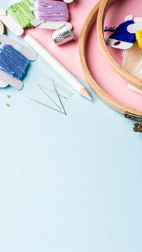 Vibrant embroidery materials including threads, needles, and hoops on a pastel backdrop, ideal for creative projects with copy space, phone background