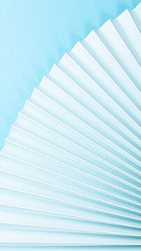 Beautifully arranged paper folds create an elegant fan shape against a soft blue backdrop, highlighting texture and design aesthetics, phone background with copy space