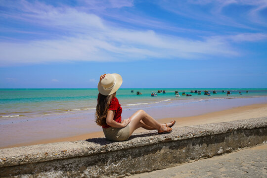 Young woman enjoying panoramic view of natural swimming pools with jangadas rafts in Joao Pessoa, Brazil