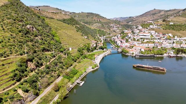 Aerial view of the Douro River with terraced vineyards and cruise boats in Pinhao, Vila Real, Portugal.