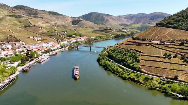 Aerial view of the Douro River flowing through Pinhao with its iconic bridge and terraced vineyards on the surrounding hills, Pinhao, Vila Real, Portugal.