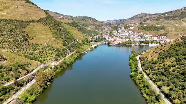 Aerial view of the Douro River flowing past the terraced vineyards and white houses of the town of Pinhao, Vila Real, Portugal.