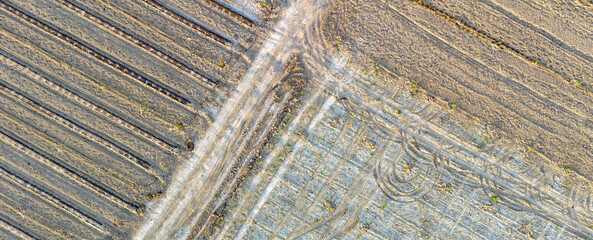 Fototapeta premium Diagonal intersection of dusty rural farm paths and plowed fields captured from above