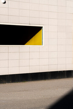 Graphic opening in a wall creates minimal space as sunlight and shadow shape geometric contrast across the architecture facade for clean layout