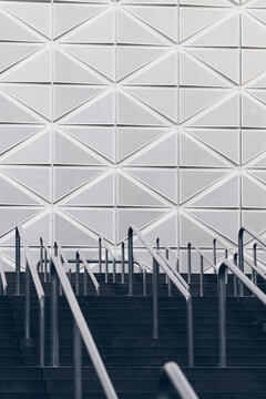 Rising stairs with handrails show geometric pattern as modern minimal architecture facade lines lead in perspective with open foreground space