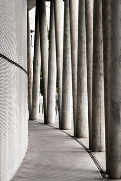 Curved concrete walkway with columns brings architecture pattern and shadow into a minimal urban perspective with generous foreground space