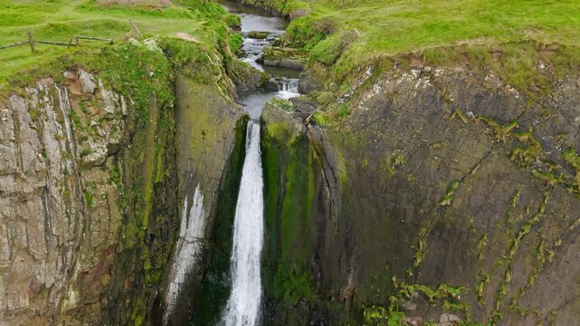 Aerial view of surroundings at Spekes Mill Mouth waterfall which is  located in a beautiful coast area of rugged valleys, high cliffs and wildflowers flourish. Drone POV of United Kingdom landscapes. 