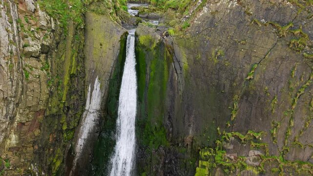 Aerial view of surroundings at Spekes Mill Mouth waterfall which is  located in a beautiful coast area of rugged valleys, high cliffs and wildflowers flourish. Drone POV of United Kingdom landscapes. 
