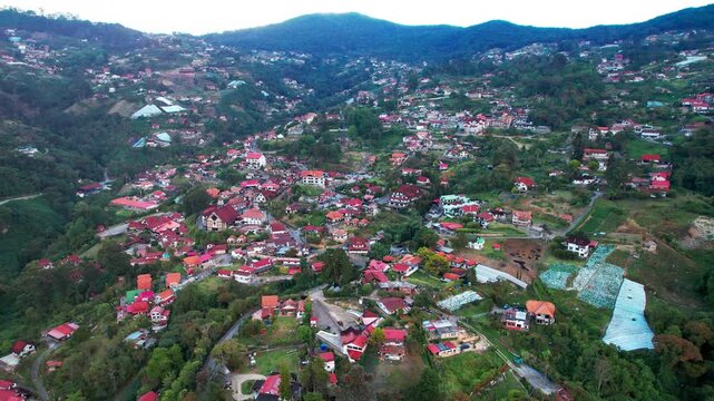 High angle drone shot over a picturesque settlement nestled in the green mountains of Aragua featuring traditional German style buildings