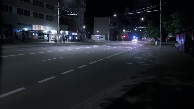 Fire truck passing red traffic signal at busy intersection urban road infrastructure. City street at night with emergency vehicle lights reflecting on asphalt surface. Urban environment
