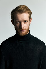 Fototapeta premium Stylish young man in a black turtleneck exudes confidence and modern fashion elegance