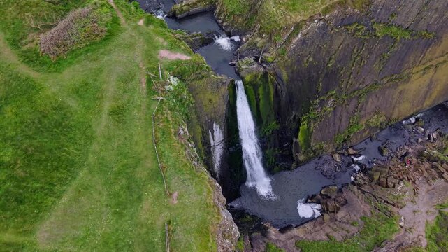 Aerial view of surroundings at Spekes Mill Mouth waterfall which is  located in a beautiful coast area of rugged valleys, high cliffs and wildflowers flourish. Drone POV of United Kingdom landscapes. 