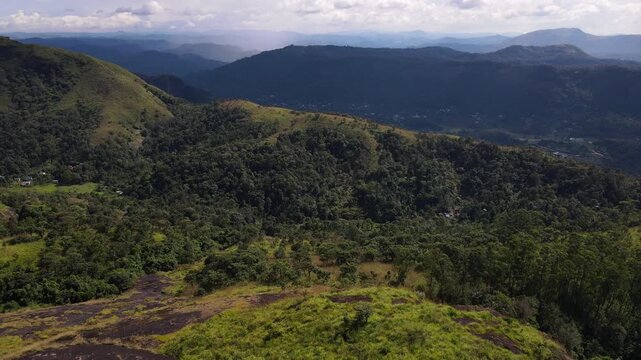 Cinematic drone orbit around lush green mountain ranges and tea plantation hills of Munnar Kerala India showcasing the rolling valleys and misty peaks