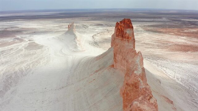 Aerial drone view of dramatic Bozzhyra rock spires in Mangistau Kazakhstan, showcasing surreal white desert, ancient ocean floor formations and otherworldly canyon landscape