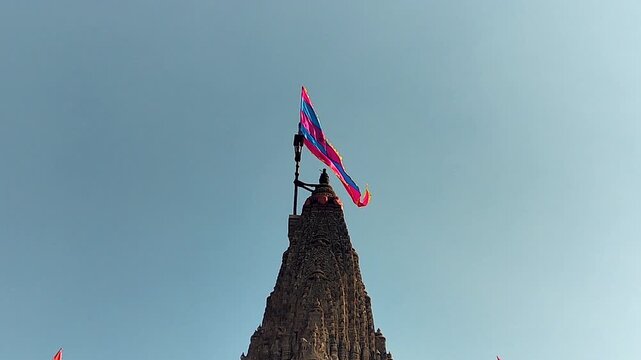Sacred dhwaja flag waving atop Dwarkadhish Temple spire in Dwarka, Gujarat. Ideal for religious content, pilgrimage visuals, Indian culture stories, and spiritual themes.