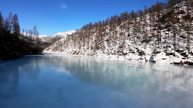 Serene winter landscape featuring a frozen lake and snow-covered mountains. A tranquil scene perfect for nature or travel projects.