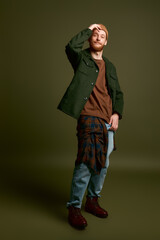 Fototapeta premium Young stylish man poses confidently against a rich green backdrop highlighting modern fashion trends.