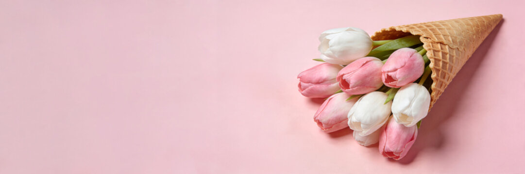 Pink and white tulips in waffle cone. Creative spring floral arrangement. Whimsical flower bouquet concept for celebrations and gifts. banner format