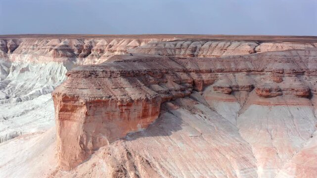 Close aerial view of layered canyon cliff face with visible erosion patterns and sediment strata in Bozzhyra Mangistau Kazakhstan, showcasing geological structure and natural rock textures