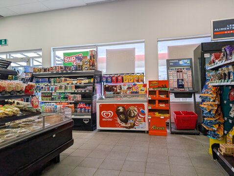 Quebec, Canada, 24 April 2026 : Aisle inside a convenience store features shelves stocked with snacks, beverages, ice cream, and lottery products.